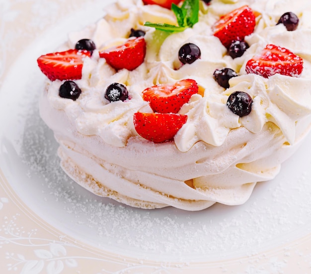 Pavlova-koekjes met room en verse bessen op het bord