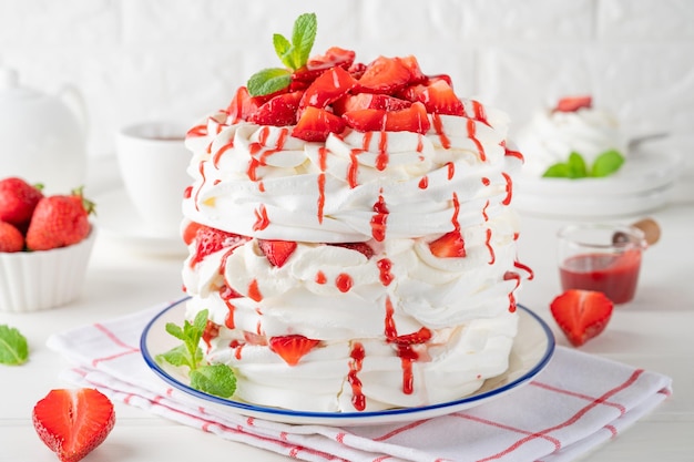 Pavlova layered cake with fresh strawberries sauce and whipped cream Summer beautiful cake