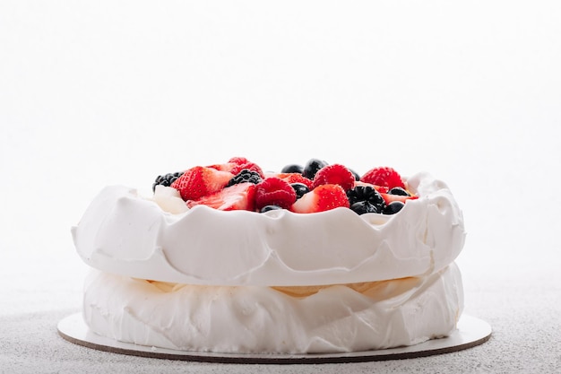 Pavlova meringue cake with fresh berries on white background