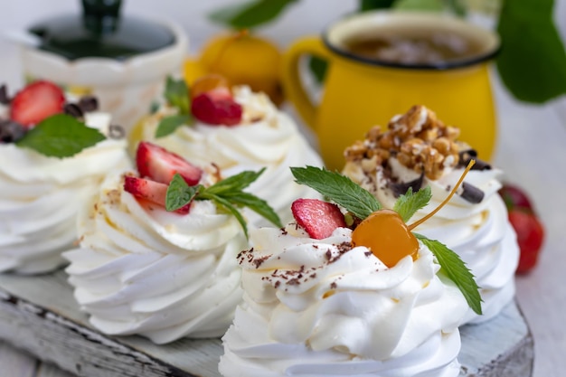 Torte di meringa pavlova con panna montata e fragole fresche foglie di menta messa a fuoco selettiva