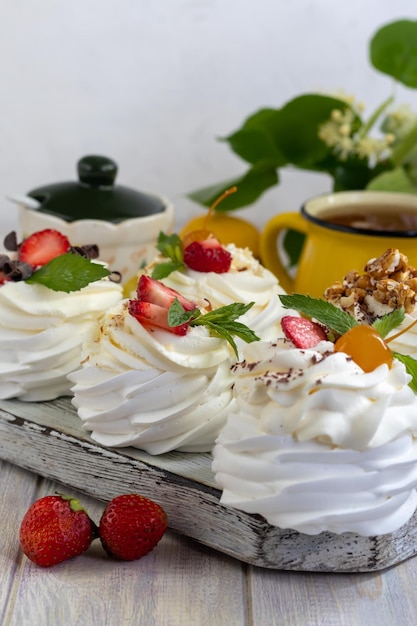 Pavlova meringue cakes with whipped cream and fresh strawberries mint leaves Selective focus