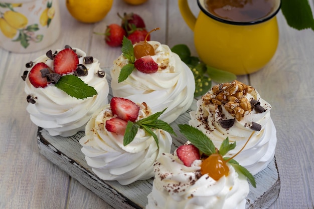 Torte di meringa pavlova con panna montata e fragole fresche foglie di menta messa a fuoco selettiva