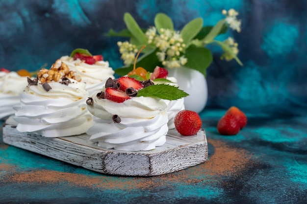 Pavlova meringue cakes with whipped cream and fresh strawberries mint leaves Selective focus