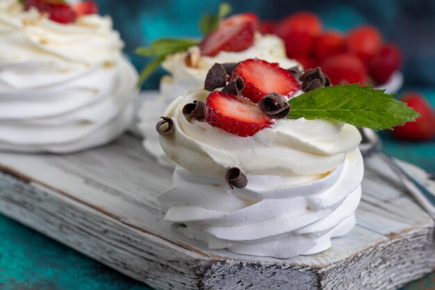 Pavlova meringue cakes with whipped cream and fresh strawberries mint leaves Selective focus