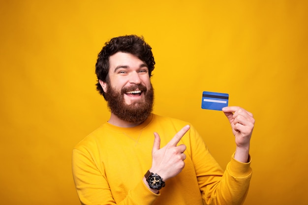 Pay with cards. Bearded man holding one is pointing at it and smiling at the camera.