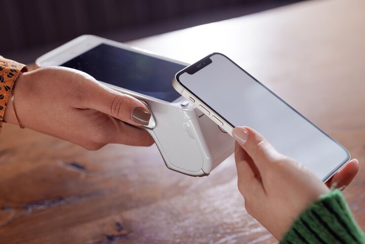 Photo payment by nfc phone a woman pays contactlessly using a phone with nfc technology wireless money transactions card machine in a womans hand on the background of a cafe