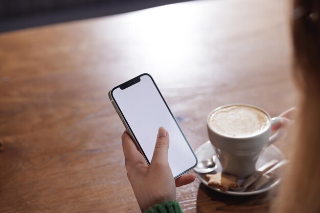 Payment by NFC phone A woman pays contactlessly using a phone with NFC technology Wireless money transactions Card machine in a womans hand on the background of a cafe