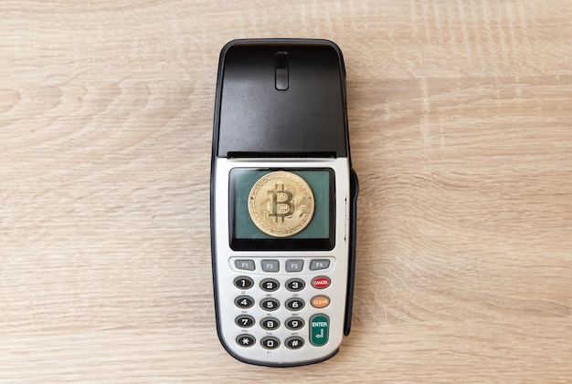 Photo payment pos terminal with bitcoin on a wooden table