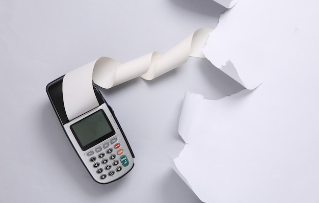 Payment terminal and torn paper sheet on gray background Copy space Top view