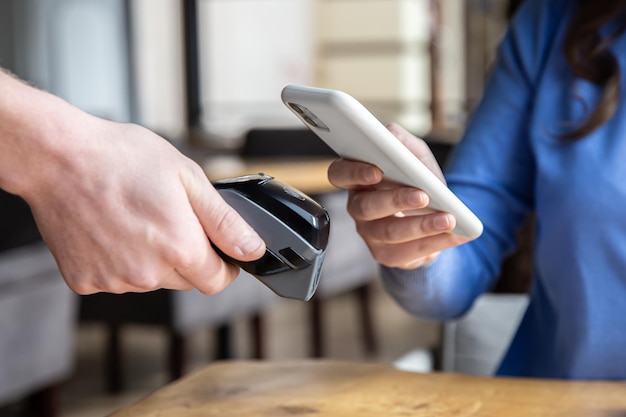 Photo paypass male hands holding black pos terminal and female brings smartphone