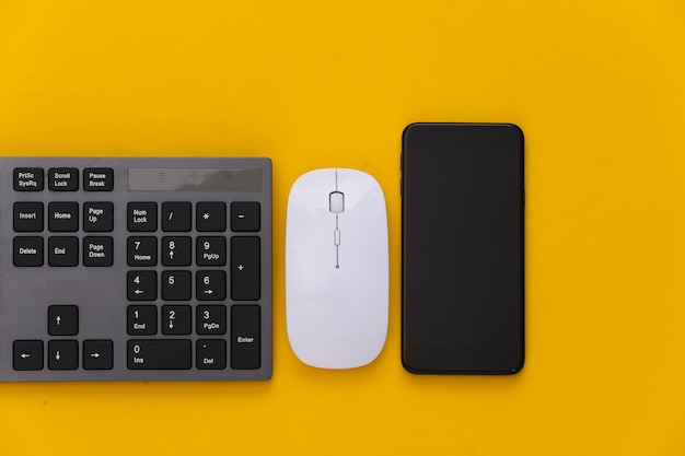 PC keyboard with pc mouse, smartphone on yellow