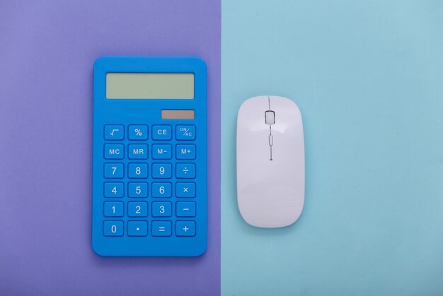 Pc mouse with calculator on purple blue background. Top view