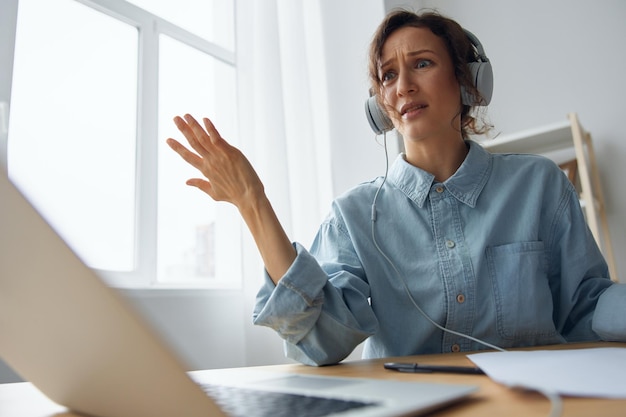 Pc software failure angry businesswoman lost all important\
documents due laptop breakdown working at home office curly\
irritated adorable lady in headphones raise hands up raging after\
crash error