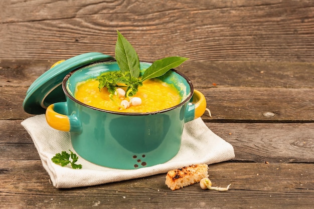 Pea cream soup in a bowl on vintage wooden background Dry legumes toast croutons and greens