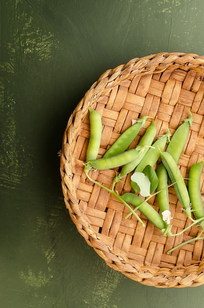 Pea pods in a basket on a green backdrop