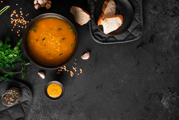 Pea soup on dark background. Soup in a black saucepan. A bowl of soup. Parsley, pepper mixture, sauce, bread. High quality photo