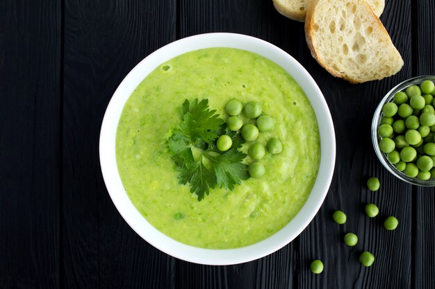 Photo pea soup in the white bowl on the black wooden background