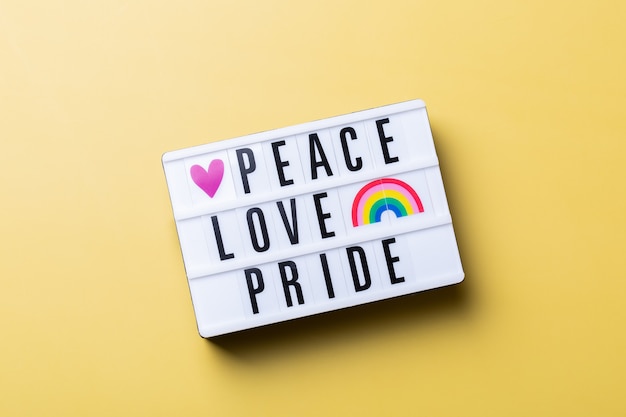 Peace love pride text rainbow lgbtq flag against yellow background