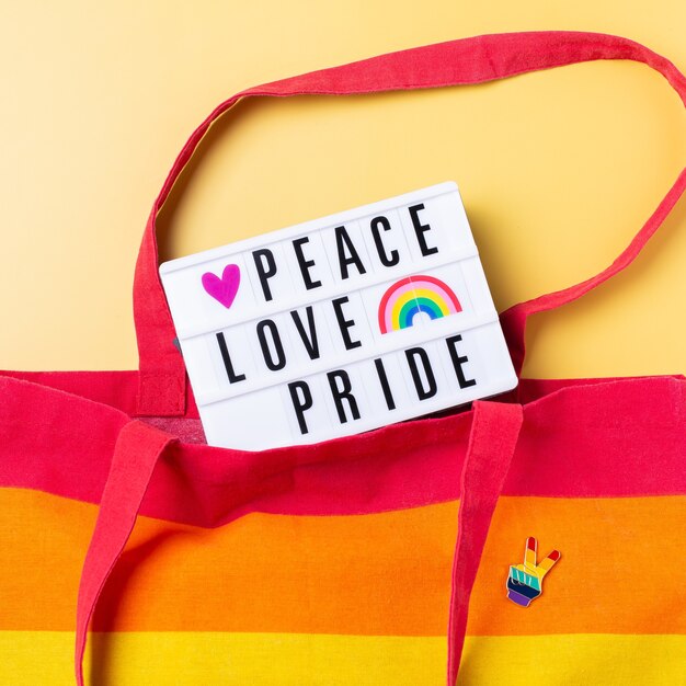 Peace love pride text rainbow reusable bag against yellow background