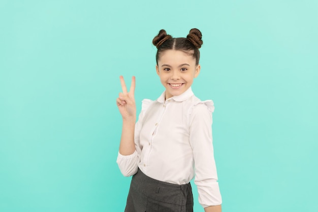 Peace maker. School age kid show V sign. Happy kid blue background. Basic education. Back to school. September 1. Knowledge day. Happy childhood.