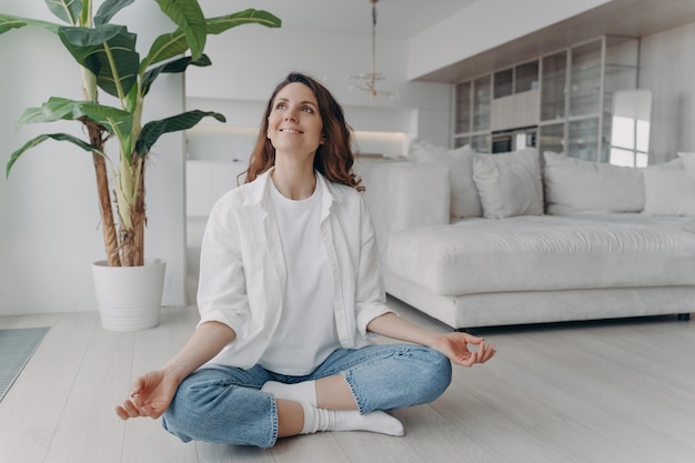 Peace of mind and mental health concept Young european woman practicing yoga on floor and smiling