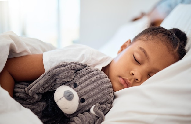 週末に自宅でおもちゃのテディと居心地の良いベッドで眠っている黒人の子供の平和の朝と健康 テディベアと快適な家の寝室で夢を見ている子供の睡眠と健康をリラックス