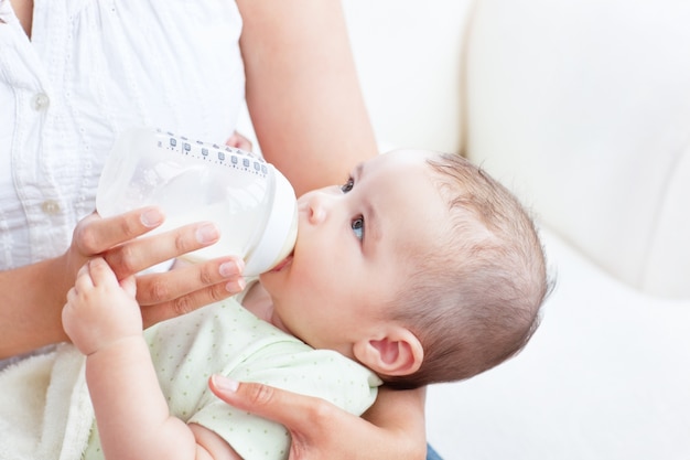 Foto neonato pacifico che si trova in braccia di sua madre che beve latte per pranzo