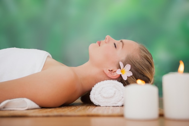 Peaceful blonde lying on bamboo mat with candles at the health spa