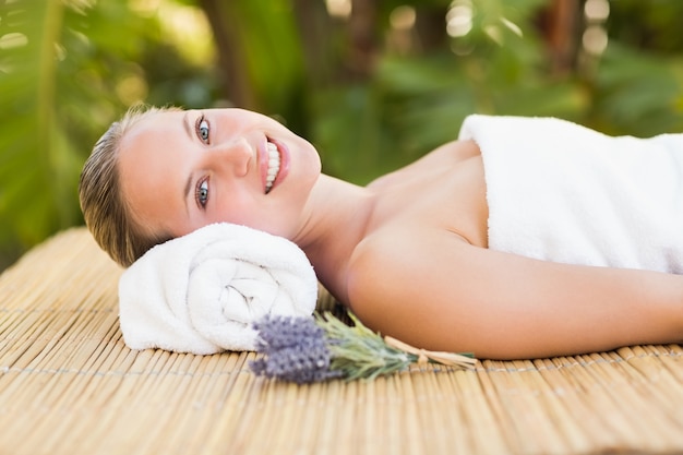 Peaceful blonde lying on bamboo mat with flowers 