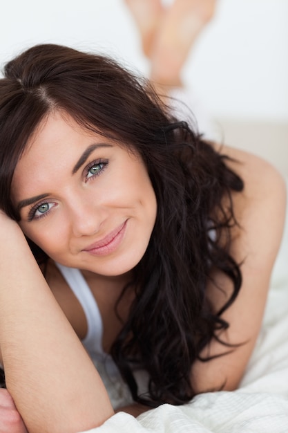 Peaceful brown-haired woman lying on her duvet