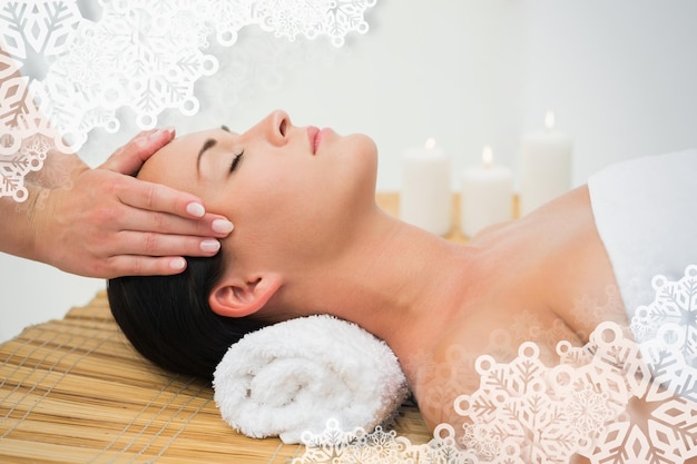 Peaceful brunette enjoying a facial massage against snowflake frame