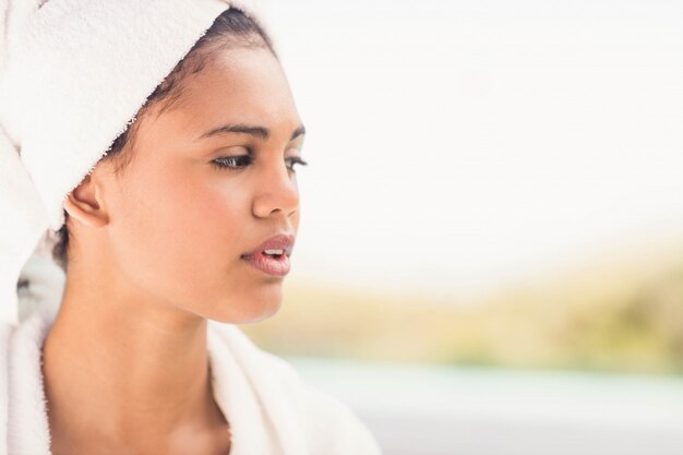 Peaceful brunette wearing white towel looking away