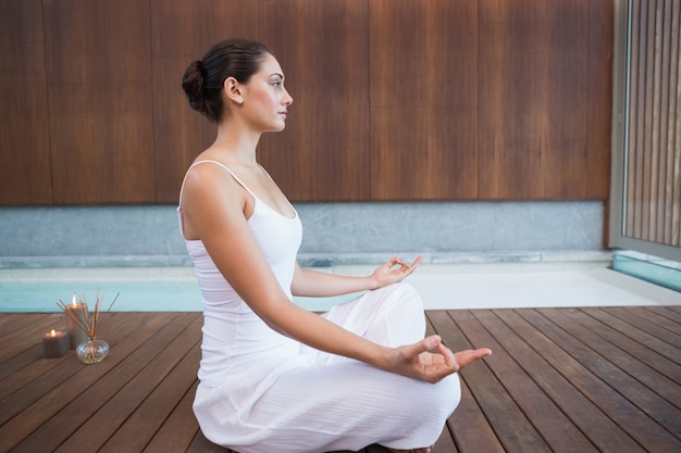 Peaceful brunette in white sitting in lotus pose 