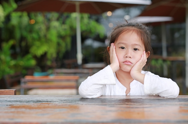 あなたを見て、木製のテーブルに横たわる平和なかわいいアジアの子供の女の子。