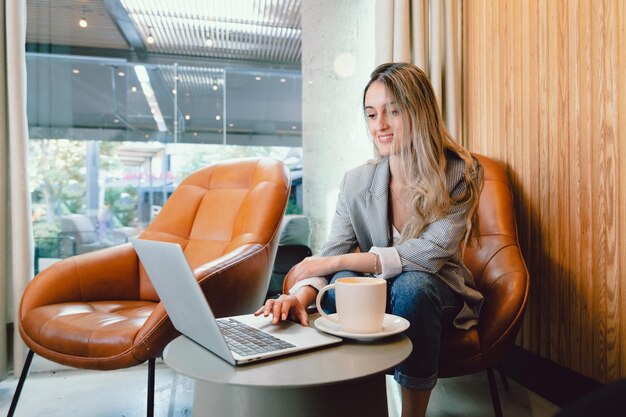 Peaceful millennial business woman using computer, with mug of coffee in modern workplace.