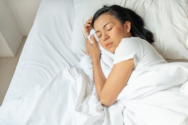 Peaceful serene young lady wear pajamas lying asleep on the bed.