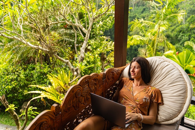 Photo peaceful view. pleased brunette girl keeping smile on her face while looking at green palms