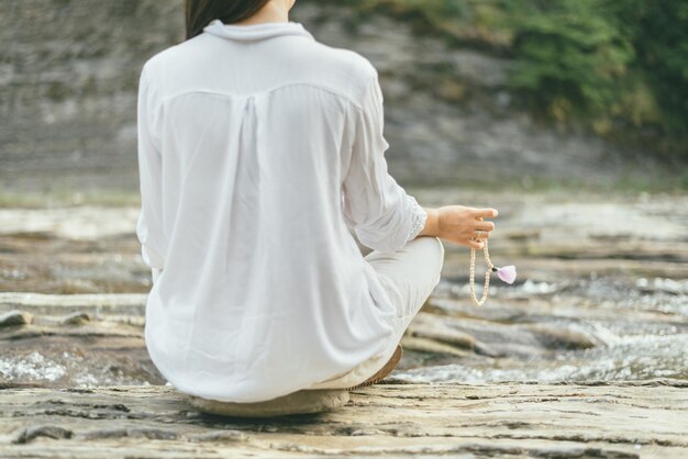 평화로운 여성이 강 근처에서 만트라 명상을 하고 있다