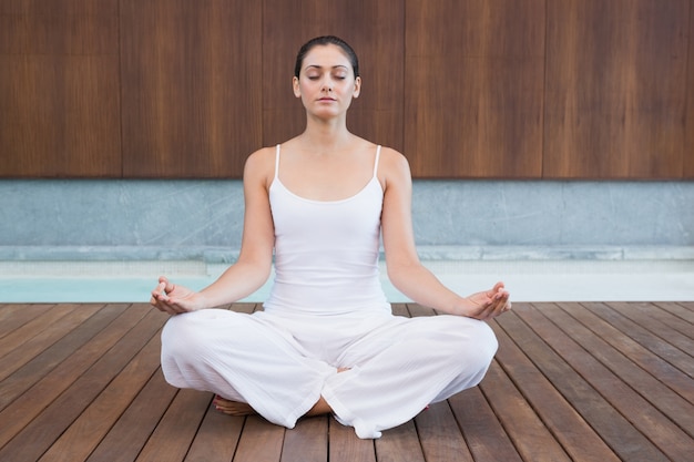 Peaceful woman in white sitting in lotus pose