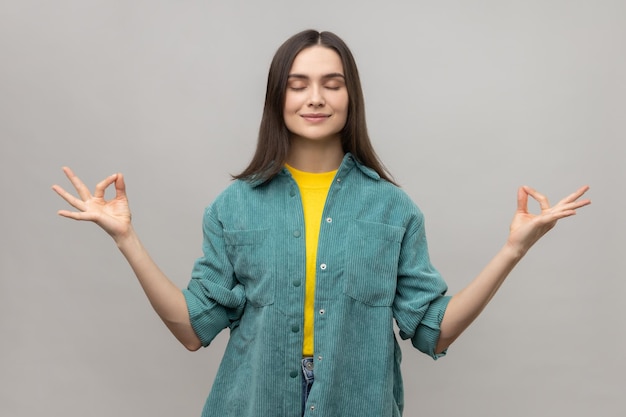 Giovane donna pacifica che si rilassa e fa un gesto di meditazione con le dita che praticano yoga