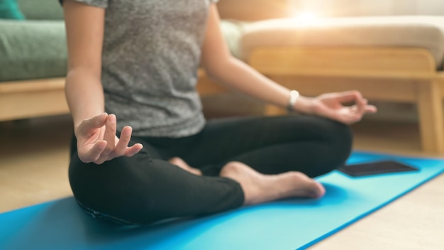 Мирная молодая женщина в спортивной одежде практикует йогу, сидя на коврике для фитнеса в позе лотоса Концепция йоги