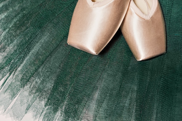 Peach ballet shoes on a green tutu. Advertising ballet school. Professional ballet background.