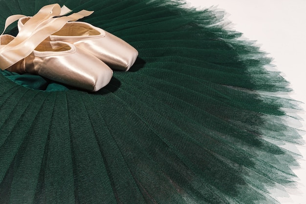 Peach ballet shoes with ribbons on a green tutu.. Advertising ballet school. Professional ballet background.