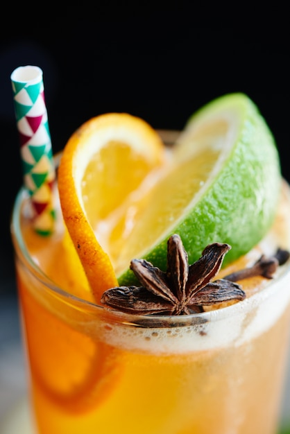 Peach black iced tea consists of vanilla syrup, spices and lemon juice in a glass closeup on dark background