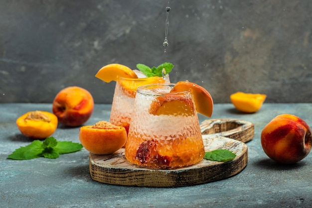 Peach cocktail with ice cubes and mint in glass Freeze motion splash drops