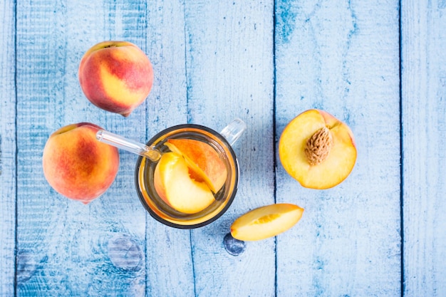 Peach compote in a glass with a straw and fruits on the table Summer organic drinks Top view