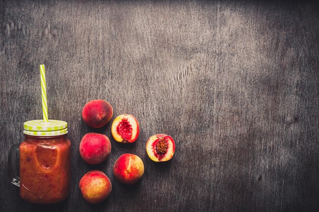 유리병에 든 복숭아 과일 스무디와 나무 탁자에 있는 빨대. 건강한 생활. 톤