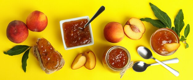 Peach jam and ingredients on yellow background