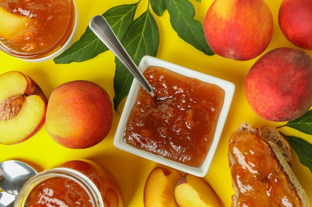 Photo peach jam and ingredients on yellow background