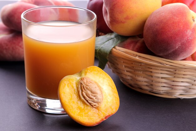 Peach juice in a glass next to a fresh peach closeup